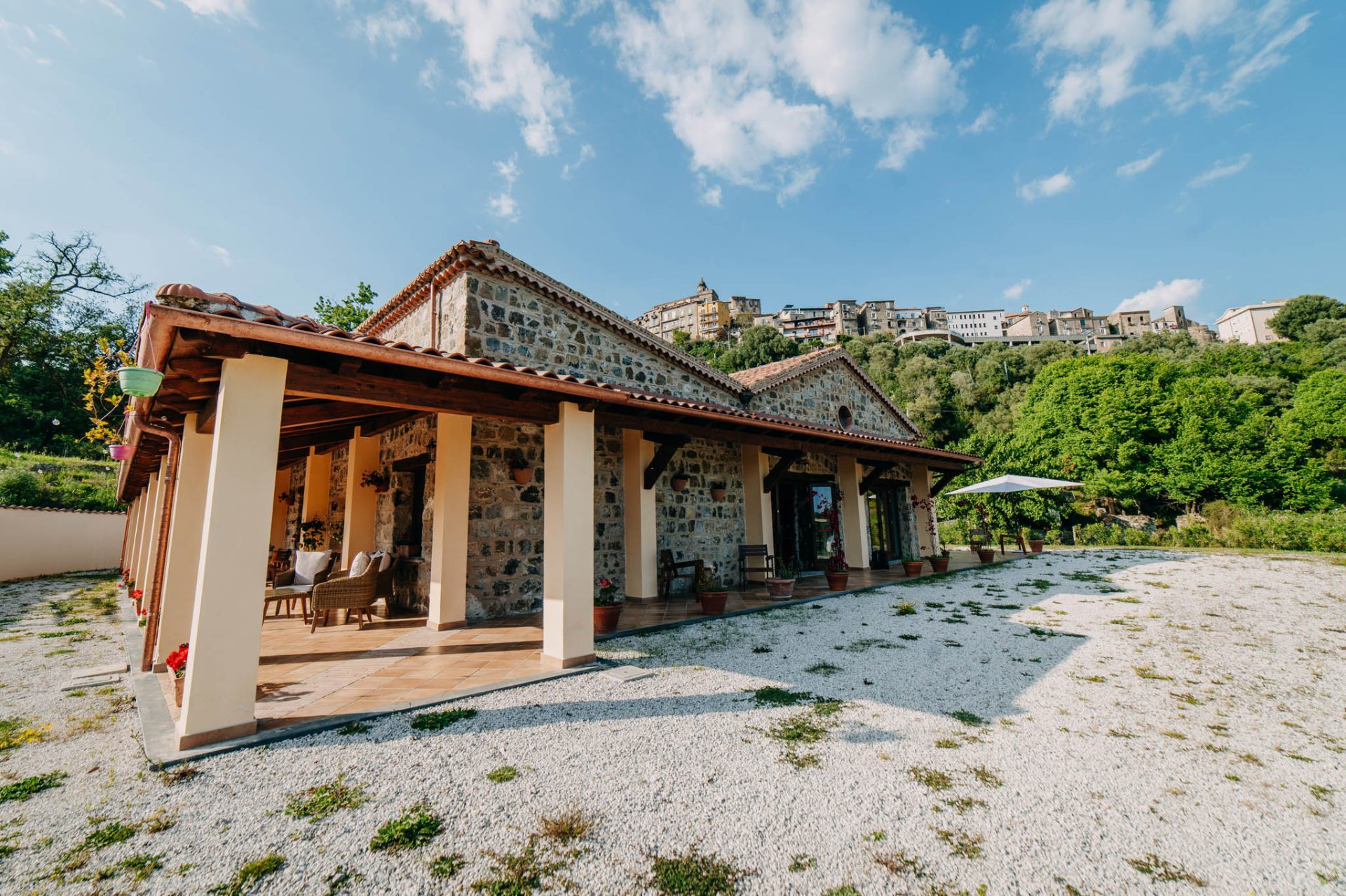 Vista laterale della struttura in pietra con portico e borgo sullo sfondo