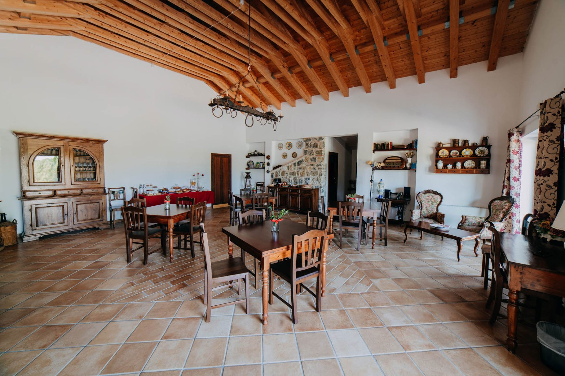 Sala comune con travi in legno, tavoli e arredi rustici